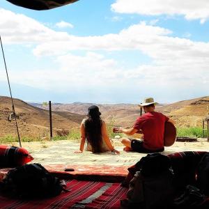 two people sitting on a table looking out over the mountains at Desert's Edge Eco Tent in Arad