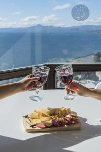 une table avec une assiette de nourriture et deux verres de vin dans l'établissement Aires del Lago, à San Carlos de Bariloche