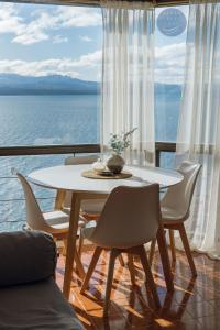 uma mesa e cadeiras num quarto com vista para o oceano em Aires del Lago em San Carlos de Bariloche