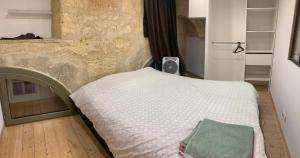 Ce lit se trouve dans un dortoir doté d'un mur en pierre. dans l'établissement chambre avec salle de bain et cuisine privée centre ville historique avec climatisation et patio, à Bordeaux