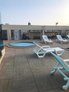 a deck with chairs and a pool on a building at Flat Palladium in São Vicente