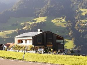 une maison sur le côté d'une route avec une montagne dans l'établissement BergNest Großwalsertal, à Raggal