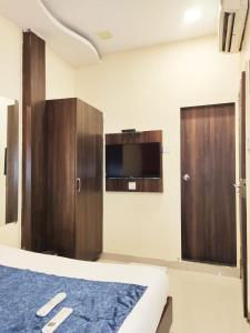 1 dormitorio con 1 cama, TV y armarios de madera en Hotel Golden Galaxy - Santacruz East, en Bombay