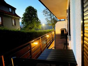 a porch with a bench and a fence with lights at STANMA Luchspartment ruhig und zentral mit großem Balkon und Parkplatz in Braunlage