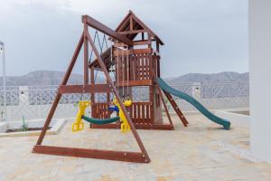 une aire de jeux avec une balançoire et un toboggan dans l'établissement Horizon Villa, à Qurayyah