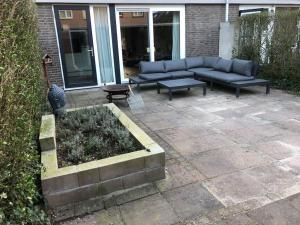 un patio con sofá azul y bancos en Compleet huis in Nijmegen, en Nijmegen