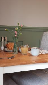 Appleton House في Thornbury: طاولة خشبية مع إناء من الزهور وكوبين