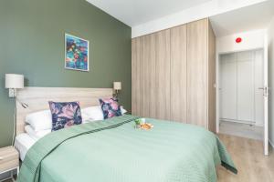 a bedroom with a bed with a green comforter at Shellter Suita Flora by Renters Prestige in Rogowo