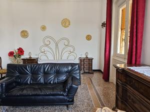 a black leather couch in a living room with red curtains at Gropallo Palace Apartments - 4 Dreams 4 You - Pieno centro - Palazzo Nobiliare Storico in Genoa