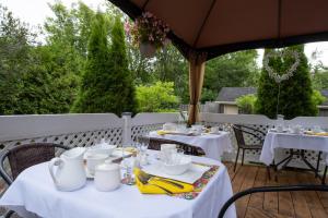 a table with white tables and chairs on a patio at Au coq du bonheur in Magog-Orford