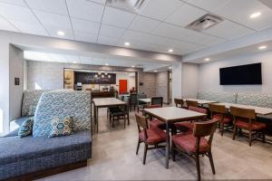 una sala de espera con mesas, sillas y TV en Hampton Inn Columbus Downtown, Ga en Columbus