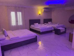 three beds in a room with purple lighting at Royal Pyramids Museum Guest House in Cairo