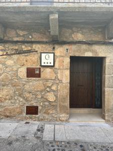 un edificio de piedra con una puerta y un reloj en él en Casa Rural De Mascoras, en Santibáñez el Alto