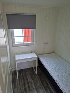a small room with a bed and a window at Hallagårdens stugby in Varberg