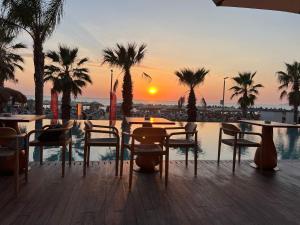 een patio met tafels en stoelen en de zonsondergang bij FRESKIA GOLEM in Golem