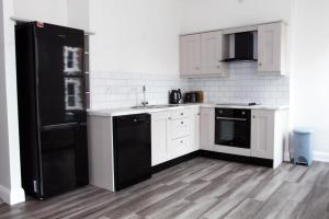 a kitchen with a black refrigerator and white cabinets at Castle gate lodge in Derry Londonderry