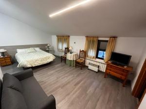 1 dormitorio con 1 cama, TV y sofá en La Antigua Vaquería, en Cuenca