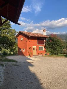ein kleines orangefarbenes Haus mit Kieseinfahrt in der Unterkunft Antico fienile in Belluno