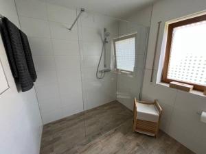 a bathroom with a glass shower with a chair at Bachgeflüster in Weilheim
