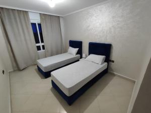 um quarto com 2 camas e uma janela em Centre Réception tanger près de la plage em Tânger