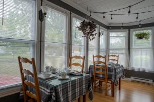 a dining room with a table and chairs and windows at Au coq du bonheur in Magog-Orford