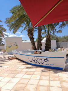 a boat sitting under an umbrella next to palm trees at Le Patio de Mezraya in Mezraya