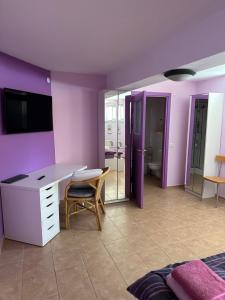 een slaapkamer met paarse muren, een bureau en een stoel bij Casa Portocalie in Cisnădie