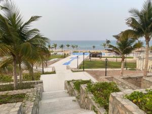 een trap naar een strand met palmbomen bij Escape Villa in As Sīfah