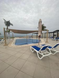 un paio di sedie e un ombrellone accanto alla piscina di Escape Villa a As Sīfah