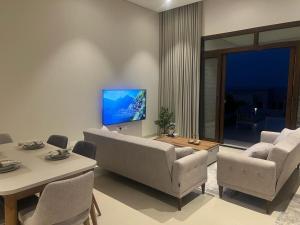 a living room with a couch and chairs and a tv at Escape Villa in As Sīfah