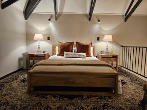 a bedroom with a large bed with two lamps on two tables at Tarry-Stone Cottages in Dullstroom