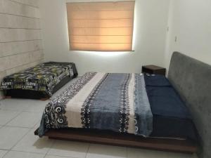 two beds sitting in a room with a window at Casa /alberca, chapoteadero, mirador, wifi in Veracruz