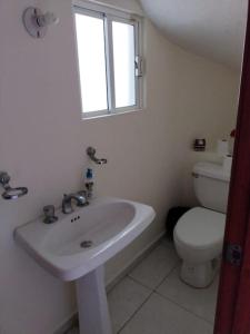 a white bathroom with a sink and a toilet at Casa /alberca, chapoteadero, mirador, wifi in Veracruz