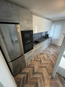 a kitchen with a stainless steel refrigerator and wooden floors at AIVI apartments in Daugavpils
