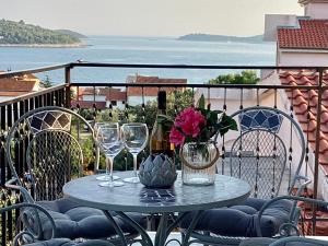 a table with wine glasses and flowers on a balcony at Apartmani Mate in Rogoznica