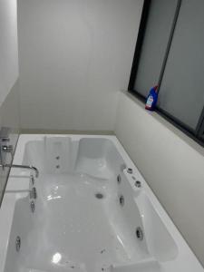 a white bath tub in a bathroom with two windows at Royal Nest Premium in Pune