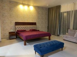a bedroom with a bed and a blue ottoman at Royal Nest Premium in Pune