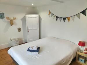 ein Schlafzimmer mit einem weißen Bett und einer blauen Schachtel darauf in der Unterkunft La maison des remparts in Falaise