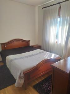a bedroom with a bed and a window with curtains at Bela moradia T3, solarenga e espaçosa 