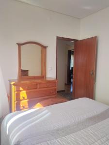 a bedroom with a wooden dresser and a mirror at Bela moradia T3, solarenga e espaçosa 