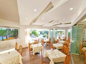 a restaurant with white tables and chairs and windows at Eco Hotel Montemerlo in Fetovaia