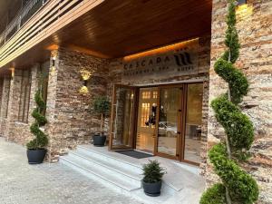Hotel Cascada BAILE OLANESTI في بايل أولانستي: مدخل إلى مبنى يوجد أمامه نباتات الفخار