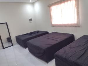 1 Schlafzimmer mit 2 Betten und einem Fenster in der Unterkunft Família Coelho Hospedagem in Igaratá
