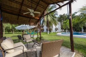 um pátio com cadeiras, um guarda-sol e uma piscina em Mayan Secret Hotel Boutique em Chetumal