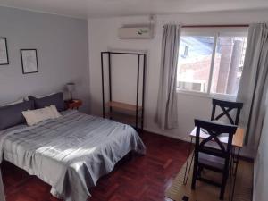 ein Schlafzimmer mit einem Bett, einem Fenster und einem Stuhl in der Unterkunft Monoambiente 76 in Mendoza