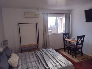 Schlafzimmer mit einem Bett, einem Tisch und einem Fenster in der Unterkunft Monoambiente 76 in Mendoza