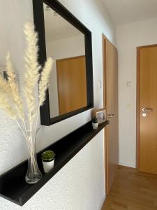 a mirror on a wall with a vase on a shelf at Nordlicht in Wilhelmshaven