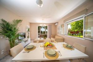 a dining room with a white table and chairs at Gaia Residences with lush garden and pool in Argostoli