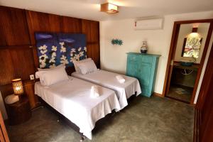 a bedroom with two beds and a blue painting on the wall at Boa Village- Bungalow com Piscina Natural- Praia de Algodões in Marau +18 photos