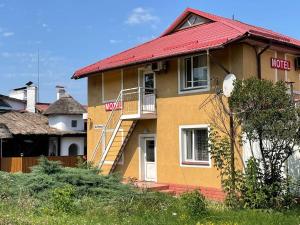een geel huis met een rood dak en een trap bij Motel in Hoshcha